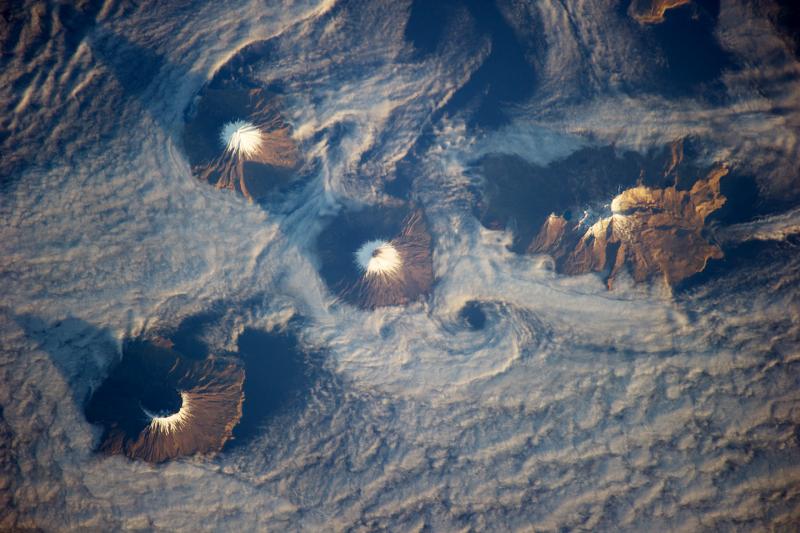 Carlisle, Tana, Cleveland, and Herbert volcanoes are all visible in this image, taken from the International Space Station on November 15, 2013. Carlisle is in the upper left, and Tana the upper right. Just left of Tana is Cleveland. Tana and Cleveland form the eastern and western halves of Chuginadak Island, and are joined by a small isthmus. The peak and island in the lower left is Herbert.