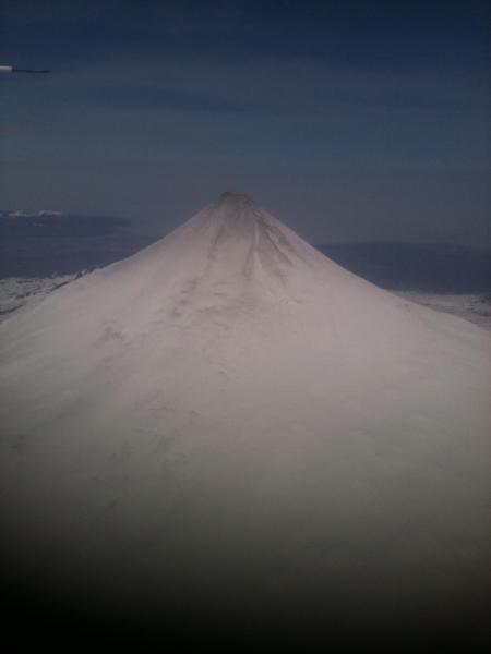 Aerial view of Shishaldin Volcano on May 14, 2015.  Note the gray discoloration of the upper flank snow and ice cover.  This material is most likely ash produced by low-level eruptive activity within the summit crater. 