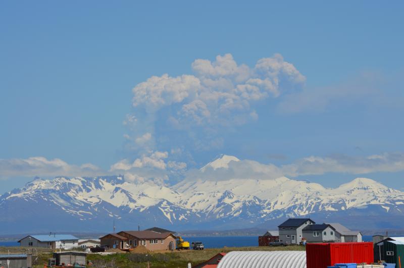 Eruption of Pavlof Volcano as viewed from Cold Bay, Alaska, 37 miles southwest of the volcano.  Lava fountaining from the summit vent is producing accumulations of spatter that gravitationally collapse to generate pyroclastic flows down the north flank (to the left of the volcano in this view).  Ash and steam are seen rising from the pyroclastic flow in this image.