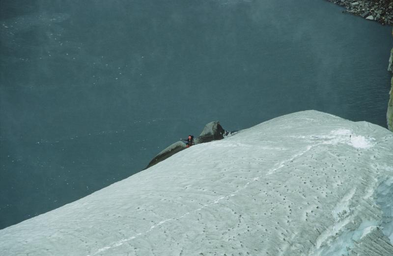 AVO geologist Game McGimsey rappelling down steep snow slope to the shore of the warm (49&deg;C, 120&deg;F), acidic (pH 2.5) lake in the Crater Peak vent of Mt. Spurr volcano to collect samples and make observations. 