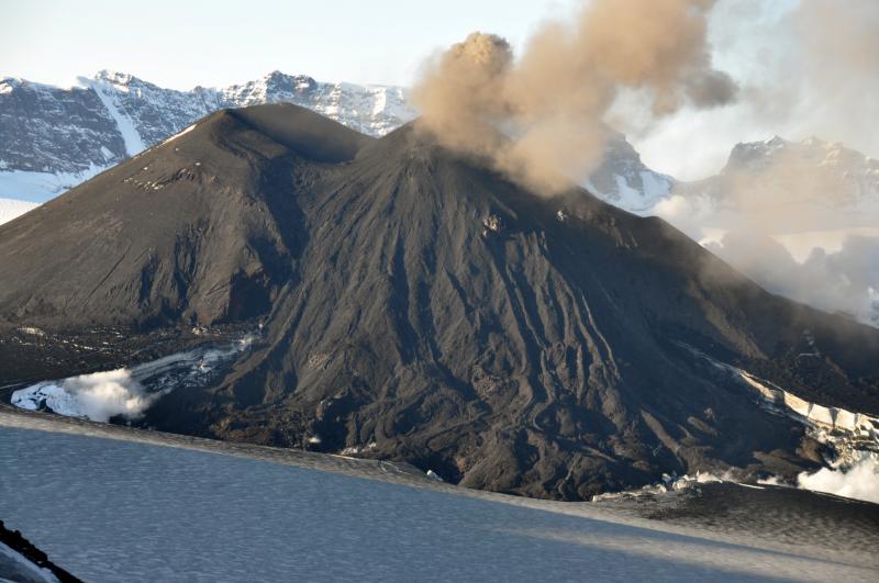 Low aerial view of the southwest flank of the intracaldera cinder cone in Veniaminof volcano.  The first lava flow of the 2013 eruption forms a wide fan across the flank, descends to the ice floor of the caldera where several coalescing ice cauldrons are forming.  Compare this image with database image 12272 taken in 2006.