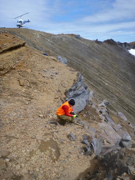 Brian Jicha (University of Wisconsin-Madison) sampling youngest lava along north rim of Akutan caldera, with orange deposits of the 1,600-yr-B.P. caldera-forming eruption above. 