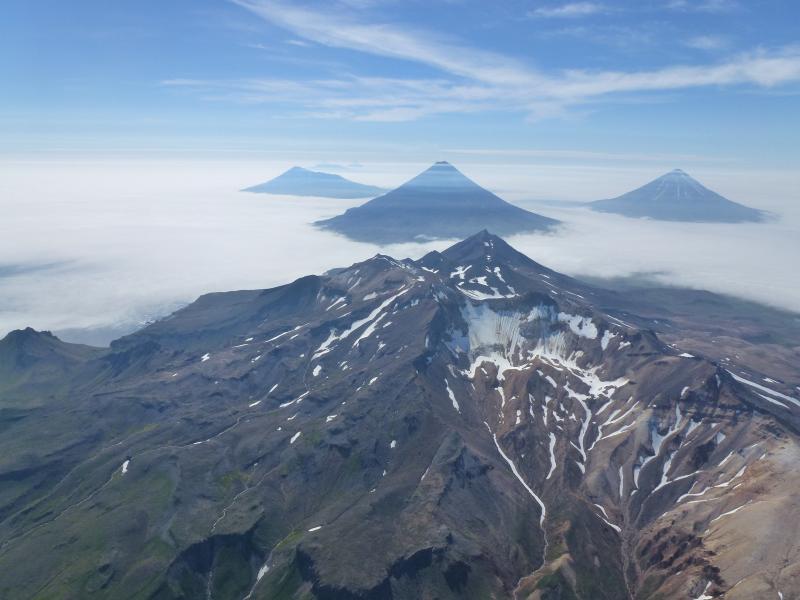 Aerial view to the west over Tana volcano. In the distance from left to right, Herbert, Cleveland, Carlisle. Photographs from fieldwork in the Islands of Four Mountains, July and August 2014.