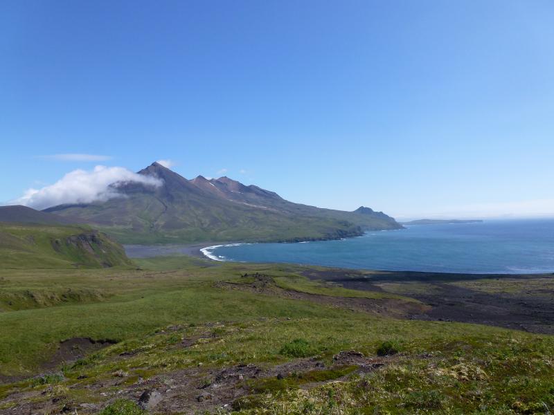 View to the east along the south coastline of Chuginadak Island from seismic station CLES.  In the distance is Tana volcano.  The bay is called South Cove which served as a good harbor under some wind and wave conditions. Photographs from fieldwork in the Islands of Four Mountains, July and August 2014.