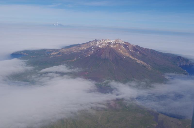 Aerial view of Tana Volcano, Vsevidof on the horizon. Photo taken during the 2014 field season of the Islands of Four Mountains multidisciplinary project, work funded by the National Science Foundation, the USGS/AVO, and the Keck Geology Consortium.