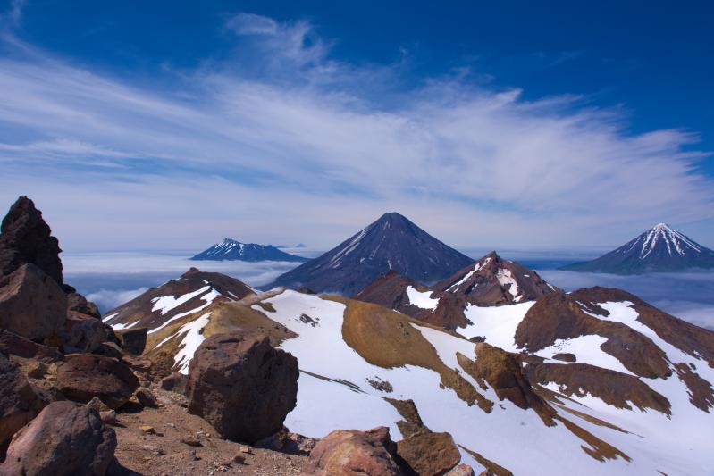 Carlisle, Cleveland and Herbert Volcanoes (right to left) seen from the summit ridge of Tana Volcano. Summits of Yunaska and Chagulak Volcanoes visible in the background. Photo taken during the 2015 field season of the Islands of Four Mountains multidisciplinary project, work funded by the National Science Foundation, the USGS/AVO, and the Keck Geology Consortium.