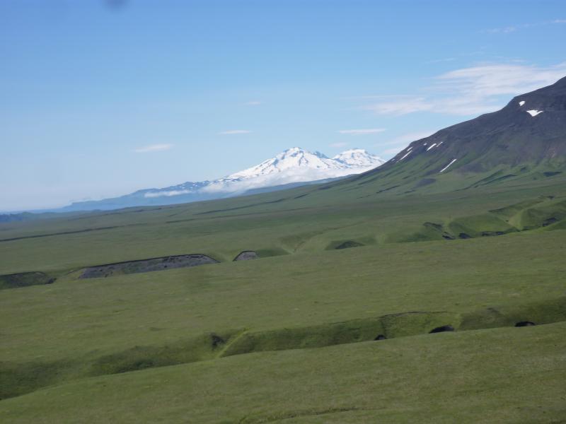 View to south from the northeast side of Umnak Island showing Recheshnoi and Vsevidof volcanoes.  The flat green terraces in the foreground are deposits from the 2050 BP caldera forming eruption of Okmok volcano.