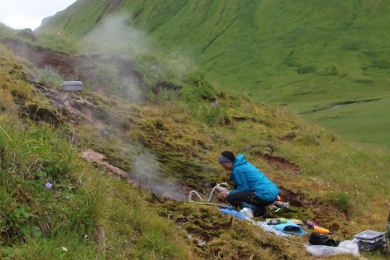 Taryn Lopez (UAF-GI/AVO) collects a gas sample from steaming ground at the Geyser Bight geothermal area on the flank of Mount Recheshnoi.