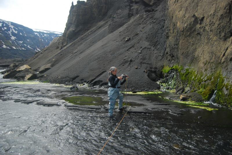 Deb Bergfeld (USGS) collects water discharge measurements at the base of Okmok&#039;s Cone D.