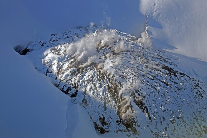 Aerial view from the east of the 2009 lava dome in the summit crater of Redoubt Volcano.  Steam and gases continue to issue from the cooling dome, which is gradually becoming buried by snow and ice accumulation.