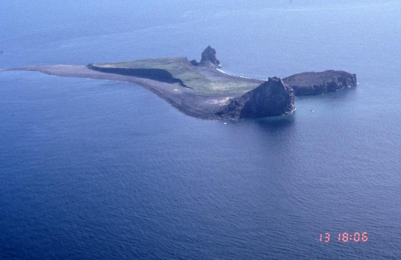 View of Bogoslof Island from the northeast.  Three lava domes are visible.  The nearest is the 1992 dome.  To the right, the flat-topped dome is from 1927.  The furthest dome is Castle Peak, which was extruded during the 1796-1804 eruption.  The raised bench is an accumulation of tephra deposits.  Bogoslof is the emerged summit of a submarine stratovolcano that rises 6,000 feet from the Bering Sea floor.