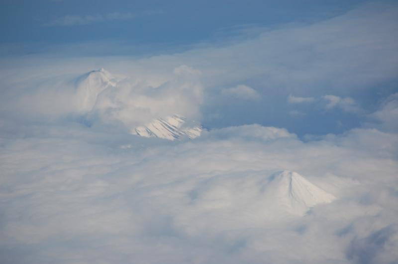 Cleveland Volcano with ground hugging steam plume (top left) and Carlisle Volcano (lower right)  of the Islands of Four Mountains group,  Aleutian Islands.  This image was taken from a passing Alaska Airlines jet two days after an explosive event at the summit of Cleveland Volcano.