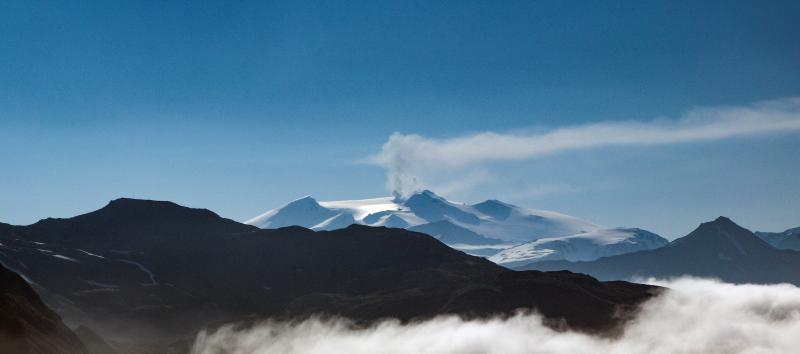 Active fumaroles at the summit of Makushin volcano emitting a plume of steam and gas; view is from Dutch Harbor on June 7, 2018.