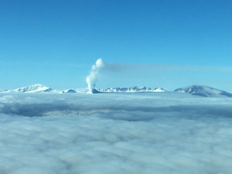 Veniaminof in eruption, September 25, 2018. Two plumes are visible; the lower one is due to the interaction of the lava flow with ice, and the upper one is coming from an active vent and contains some volcanic ash. Photo courtesy of Mari Peterson.