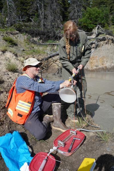 Tim Orr and Valerie Wasser attach funnel to pole in preparation for collecting gas samples at Shrub&#039;s summit pond.