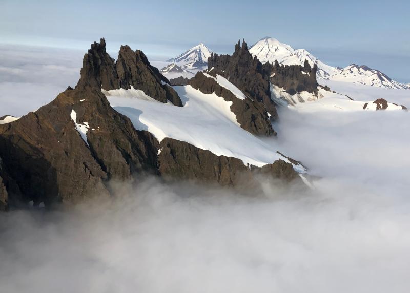 The Aghileen Pinnacles above the clouds, with Pavlof and Pavlof Sister in the background.