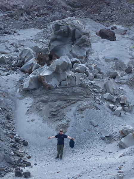 Nate Graham below a large block (bomb) below the 2006 north lava flow deposit on Augustine&#039;s flanks. Note the cross-bedded surge deposits under the block.