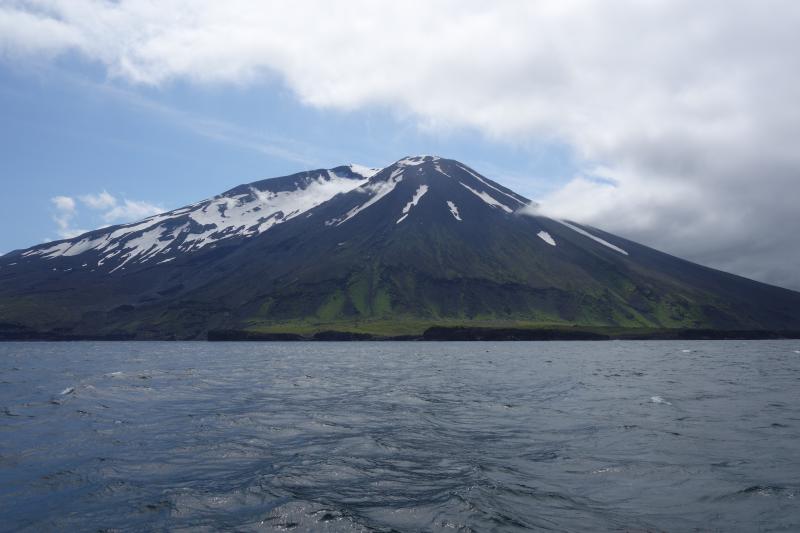 North flank of Korovin volcano showing lava flows and block and and ash flows draping the steep flanks and a flat-topped lava delta in the foreground.  Photo taken from the M/V Steadfast.
Station ID = 19AAJRS003