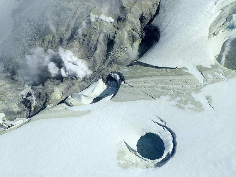 August 2019 views of the summit crater of Makushin Volcano.  Heat from vigorous fumarolic activity is melting depressions,  holes,  and caves in the glacial ice.  
