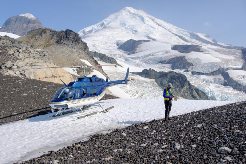 Andy Calvert (USGS, AVO) examining a deposit of dense lava and granitic xenolith bombs deposited on a saddle NW of Iliamna.