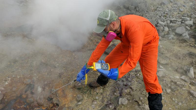 USGS gas geochemist Allan Lerner measures the temperature of a bubbling pool in the upper Glacier Valley south of Makushin Volcano.