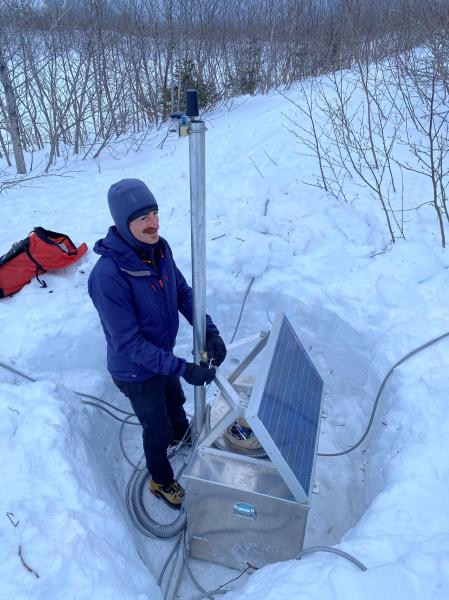 AVO technician Malcolm Herstand works on the main power and data hub for the infrasound array in Whittier. USGS photo by C. Read, February 9, 2021.