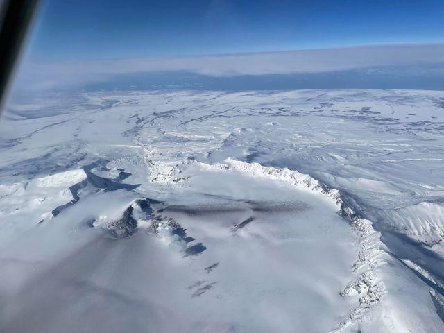 Air photo from ACE Air flight 66, March 11, 2021, 13:30 local time from approximately 21,000 feet showing ash deposits and steam plumes from Mount Veniaminof.