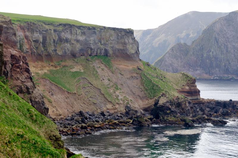 Tephra and debris flow outcrops visible below a lava flow layer on Khvostof Island.