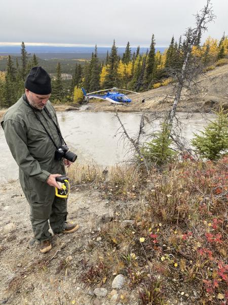 AVO geologist Tim Orr measuring temperature at a vent in the wall at the south end of the main pool at Shrub mud volcano.  Temperature is 31.1&deg;C.