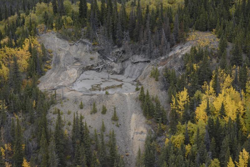 Oblique aerial view looking NW at summit pond of Shrub mud volcano in the Copper River basin west of Mt. Drum, in the Wrangell Mountains near Glennallen, AK. Mud on the back wall of the crater comes from new vents in the trees above the pond, first seen in September 2021.