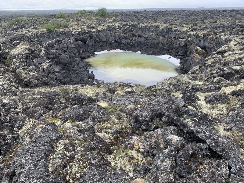 View of an inflation pit, also known as a lava rise pit, on the Lost Jim lava flow. Inflation pits form where the flow freezes solid, while the supply of molten lava to the surrounding flow is maintained, allowing the surface crust to continually thicken &ndash; a process common to pahoehoe lava flows called inflation. inflation pits are therefore places where the flow did not inflate (thicken).