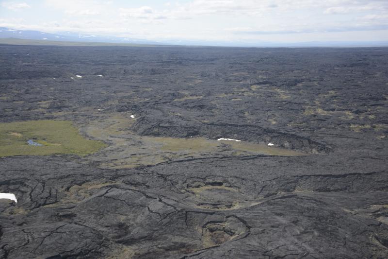 Oblique aerial view of the Lost Jim lava flow. While the crust pahoehoe lava flows is generally smooth, they commonly have a hummocky, undulating surface caused by differing amounts of lava flow inflation. Inflation is a process where the supply of molten lava within the core of the flow is maintained, allowing the crust to continually thicken until the supply is cut off. 