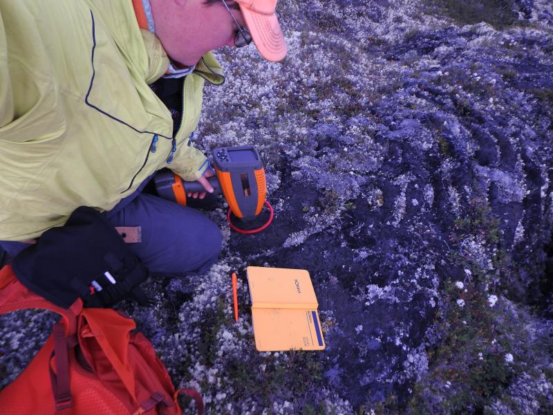 University of Idaho geologist Erika Rader uses a portable visible near-infrared spectrometer at the Lost Jim lava flow to measure the amount of light reflected by the lava flow surface. The amount of light tells us how crystalline or glassy the lava flow is, which is useful for understanding the cooling history of lava erupted into the unique arctic environment.