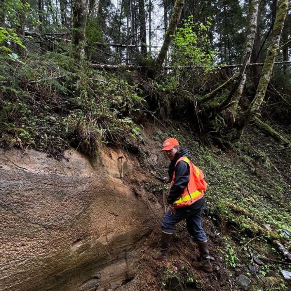 USGS geologist and AVO Scientist-in-Charge Michelle Coombs examines a Late Pleistocene tephra deposit from Mount Edgecumbe, May 3, 2022. Photo courtesy of Jacyn Schmidt, Sitka Sound Science Center.