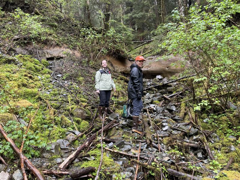 Michelle Coombs, USGS/AVO and Jacyn Schmidt, Sitka Sound Science Center, approach an outcrop of tephra from Mount Edgecumbe, May 3, 2022. 