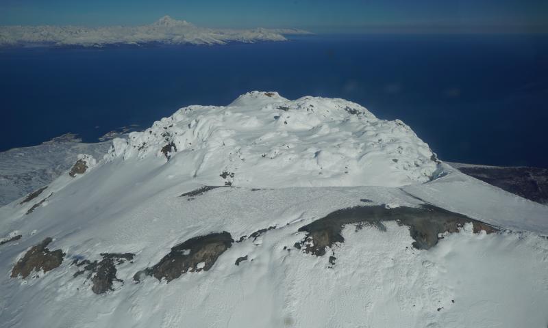 Augustine summit with Iiamna in background. Station AUSS with a lot of snow/ice build up can be seen center right of image.