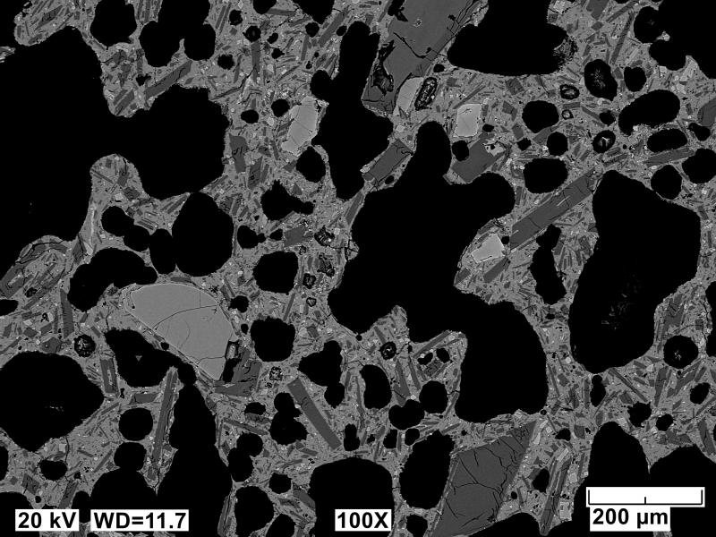 Backscatter electron polished mount image of an Edgecumbe basalt scoria clast (sample 81ARJ073A). Image shows a typical crystalline and vesicular (black areas) groundmass. Light gray crystals are olivine and dark gray crystals are plagioclase. Image acquired on an JEOL 6510LV SEM at 20 kV, 12 mm working distance, spot size of 65, and in BEC imaging mode.