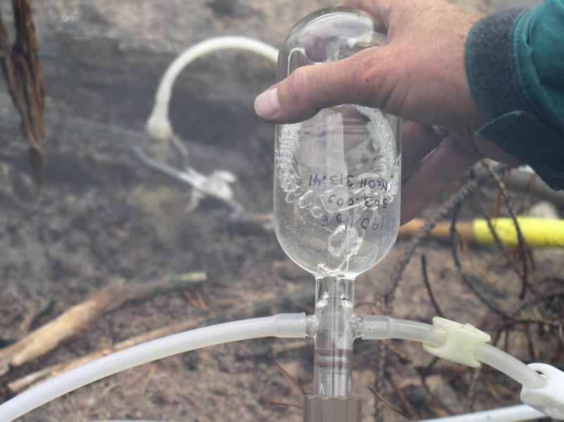 Photograph of volcanic gases being collected in a sample bottle. Photo by Deb Bergfeld, USGS.