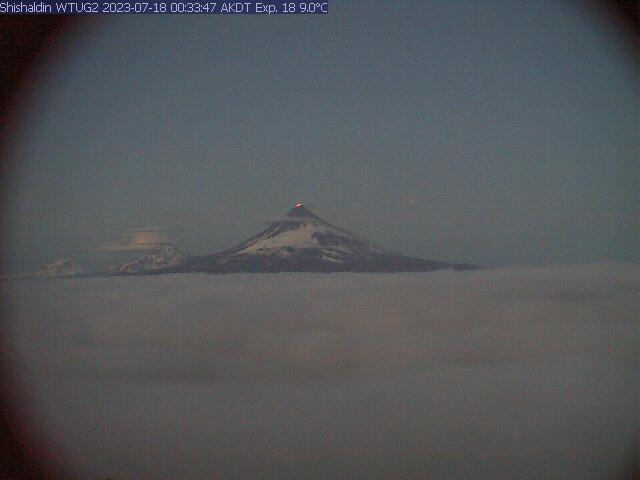 Glowing from lava erupting within the summit crater of Shishaldin around 12:30 am on July 18, 2023, as seen from the WTUG webcam located NW of the volcano. 