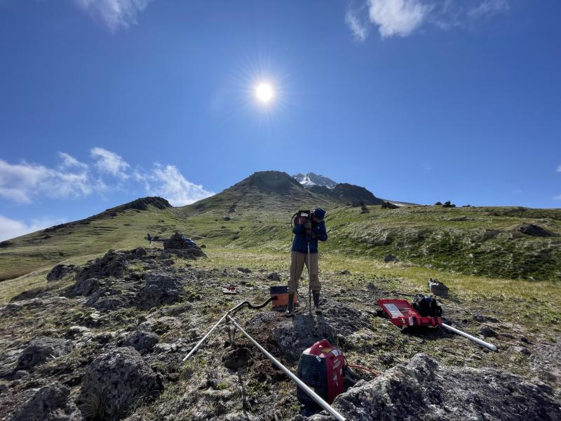 AVO field team installing a new GPS monument at site GSSP to monitor changes in Great Sitkin Volcano, western Aleutians.  The summit of the volcano is visible in the background.