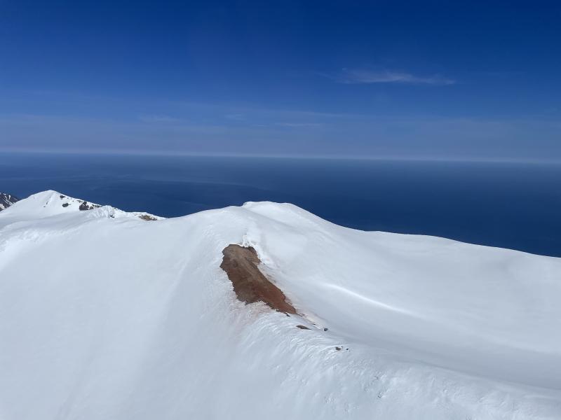 Snow-free ground at the summit of Takawangha volcano (this is on the south edge of crater #5 from the Coombs et al., 2003 report).  This area may be scoured clear of snow compared to its surroundings, or there may be some other factor such as dirt blowing onto the snow or elevated ground heat flux that causes the snow to melt more quickly than elsewhere.