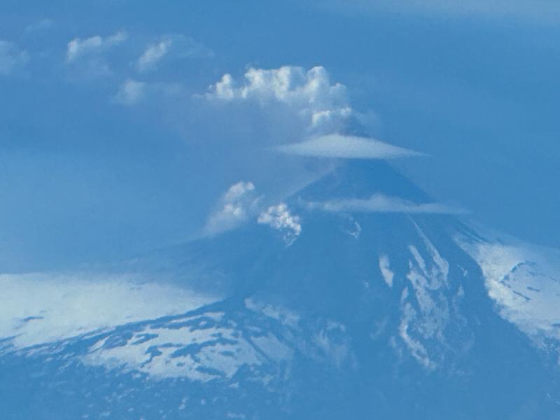 Zoom photo of Shishaldin Volcano on July 18, 2023, as an ash-rich plume erupted, taken from the air. View from the north of Shishaldin, with the ash-rich plume extending to the southeast.