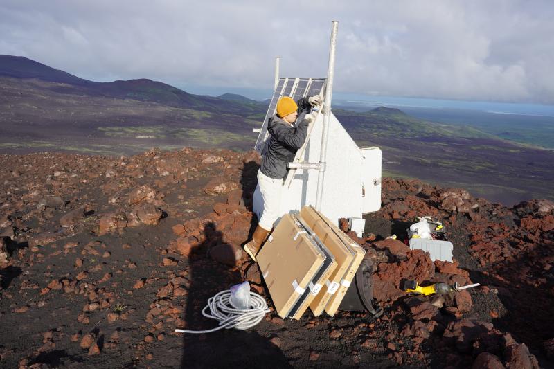Darren Tan (UAF/GI) changes out smashed solar panels at AVO site SSLN, north of Shishaldin Volcano.