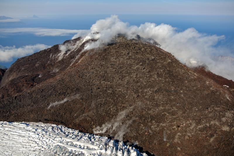 Oblique view of Great Sitkin Volcano looking west at the active lava flows in the crater. Photo taken on September 1, 2023 during a helicopter overflight by AVO geologists. The currently active lobe of the flow field is visible moving into the crater ice field on the lower part of the image.