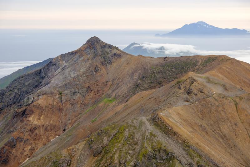 Mount Moffett summit looking east during a helicopter overflight in September, 2023. Adagdak is visible partially covered by clouds in the background, with Great Sitkin visible on the horizon (upper right).