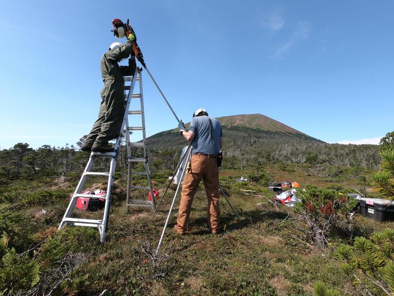 Installation of AVO&#039;s new seismic and GNSS network at Mt. Edgecumbe volcano, August 20-29 2023.   AVO field technician Max Kaufman and UAF Geodesy professor Ronni Grapenthin construct a new GNSS antenna monument at site EDES on the east flank of the mountain. 12 ft long by 1&quot; stainless steel rods are driven 7 ft into the muskeg, and welded together at the top.  Mt Edgecumbe sits in the background.  
