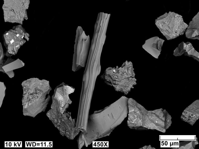 Scanning electron microscope image of Shishaldin ash that fell on the R/V Sikuliaq approximately 300 km NE of Shishaldin on August 26, 2023 (Event 8 of the 2023 eruption). Centered is a elongate glassy ash grain suggesting highly fluid particles erupted.