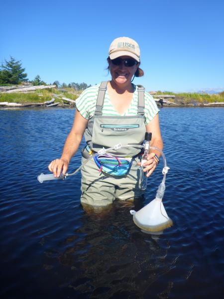 Laura Clor collects a gas sample in an evacuated bottle for chemistry analysis from the &quot;Bubbling pond&quot; on Kruzof Island.