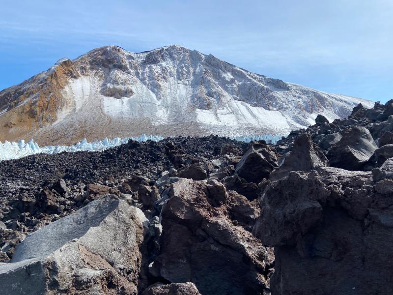 Surface of the active blocky lava flow field on Great Sitkin on September 1, 2023, with the lava-ice contact and summit of Great Sitkin in the background.