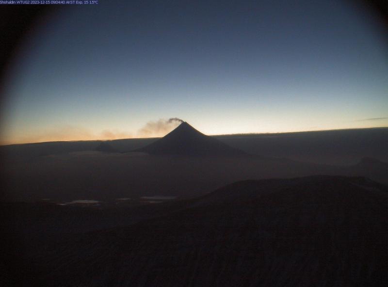 Clear early morning view of Shishaldin, showing emissions (most likely steam) from the summit backlit against the sky.